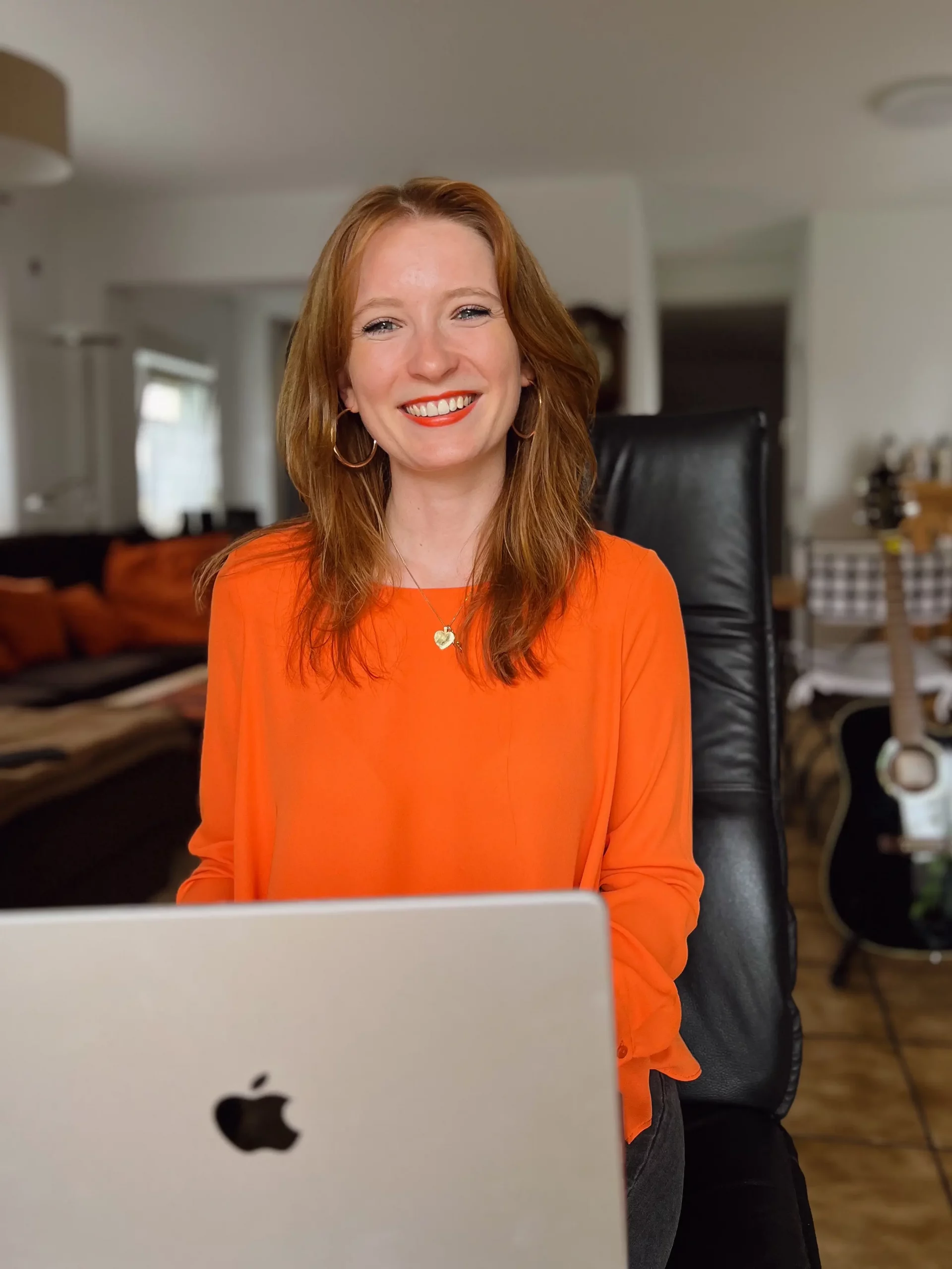 Leonie Connects - smiling at the camera with her laptop on her lap